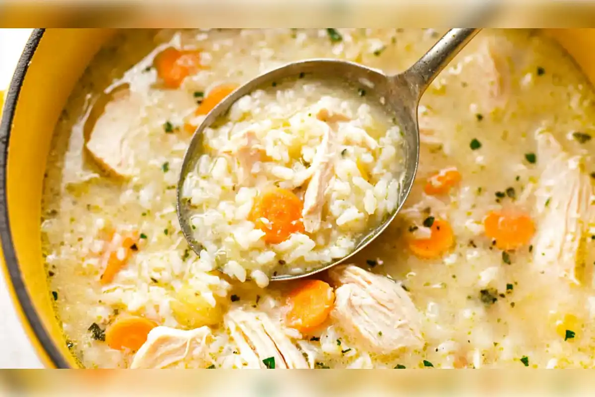 A close-up of a spoonful of chicken and rice soup with carrots, featuring tender pieces of chicken and perfectly cooked rice in a rich broth. This comforting dish showcases the ideal type of rice that holds up well in soup, maintaining its texture without becoming mushy.