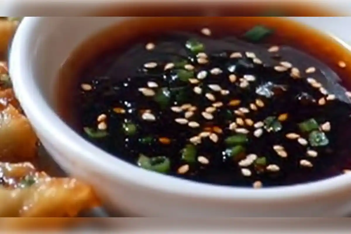 "Close-up of a bowl of teriyaki sauce topped with sesame seeds and chopped green onions, ideal as a marinade or dipping sauce.